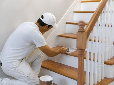 Painter painting a wooden staircase indoors